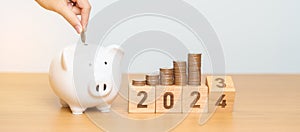 Happy New Year with piggy bank and flipping 2023 change to 2024 block. Resolution, Goals, Plan, Action, Money Saving, Retirement