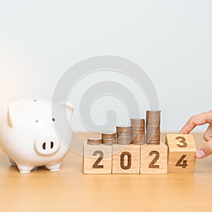 Happy New Year with piggy bank and flipping 2023 change to 2024 block. Resolution, Goals, Plan, Action, Money Saving, Retirement