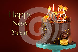 Happy New Year's Eve 2022 chocolate cake decorated with gold burning candles