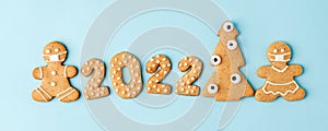 Happy New Year`s set of numbers 2022, gingerbread man in face mask from ginger biscuits glazed sugar icing decoration on blue