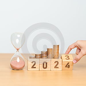 Happy New Year with sandglass and flipping 2023 change to 2024 block. Resolution, Goals, Plan, Action, Money Saving, Retirement