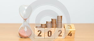 Happy New Year with sandglass and flipping 2023 change to 2024 block. Resolution, Goals, Plan, Action, Money Saving, Retirement