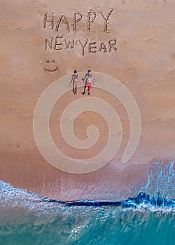 Happy new year sign on the beach with couple in the sand and chritmas hat in Thailand on the beach