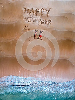 Happy new year sign on the beach with couple in the sand and chritmas hat in Thailand on the beach