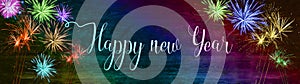 Happy new Year Silvester background banner panorama long- Colorful firework on rustic wooden texture in rainbow colors