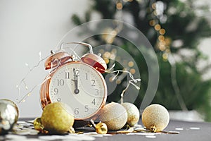 Happy New Year! Stylish retro clock, christmas glitter baubles and golden lights on moody background. New year party concept.