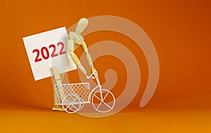 2022 happy new year symbol. Wooden clothespin, white sheet of paper with number 2022. Miniature bicycle model. Beautiful orange