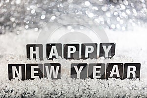 Happy new year text on snow, abstract bokeh lights background