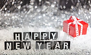 Happy new year text on snow, abstract bokeh lights background