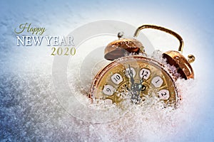 Happy New Year 2020 text and a vintage alarm clock in the snow shows five minutes before twelve, concept greeting card with copy