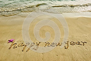 Happy new year written in beach