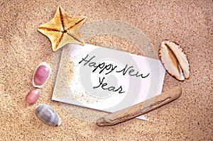 Happy new year, written on a note in the sand