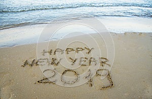 Happy new year written on the sand.