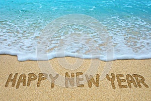 Happy new year written on sandy beach photo