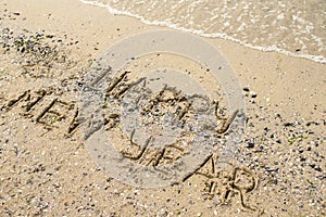 Happy new year written on tropical beach sand, copy space.