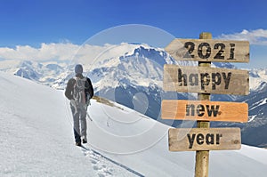 2021 happy new year written on a postsign with a hiker walking on the snow photo