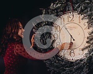 Happy New Year. young woman looks at the clock in anticipation of midnight December