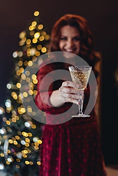 Happy New Year. young woman looks at the clock in anticipation of midnight December. Girl with champagne