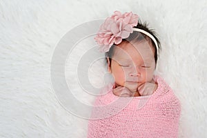 Happy newborn baby girl sleeping in cloth wrap blanket on bed