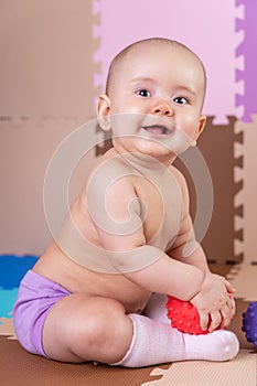 Happy newborn baby sitting on the floor and laughing