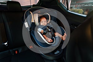 happy newborn baby sitting in infant car seat, safety chair travelling