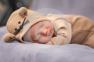 Happy newborn baby weaing cute Mouse costume lying sleeps on a grey blanket comfortable and safety.Cute Asian infant sleeping and