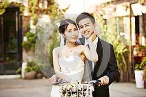 Asian newly wed couple riding a bicycle
