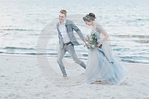 Happy newly-weds are having fun and running by the sea