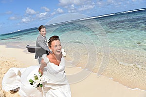 Happy newly-weds running on the caribbean beach