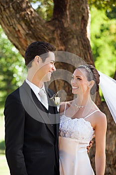Happy newlywed couple standing in park