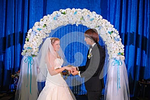 Happy newlywed couple standing in wedding arch