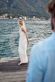 Happy newlywed couple on wooden jetty by sea. Beautiful bride feeling joyful. Newlywed coupe on honeymoon. Wedding, travel,
