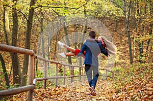 Happy newlyweds couple in love in forest park having fun, guy carries girl in his arms