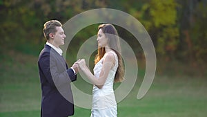 Happy newlyweds is enjoying each other on sunny day in park. Man kisses the hands of his beloved