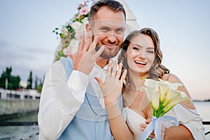 happy newlyweds exchange rings. beautiful wedding ceremony by water on dock.