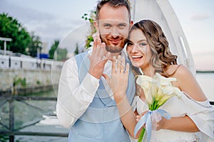 happy newlyweds exchange rings. beautiful wedding ceremony by water on dock.