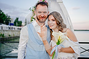 happy newlyweds exchange rings. beautiful wedding ceremony by water on dock.