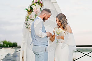 happy newlyweds exchange rings. beautiful wedding ceremony by water on dock.