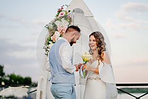 happy newlyweds exchange rings. beautiful wedding ceremony by water on dock.