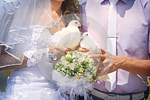 Happy newlyweds holding white doves