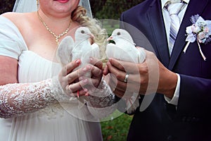 Happy newlyweds holding white doves