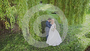 Happy newlyweds hug kiss in park.