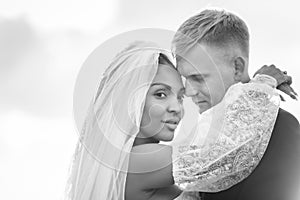 Happy newlyweds hugging in the rays of the setting sun, black and white version