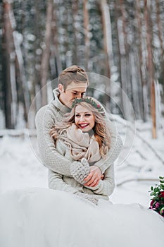 Happy newlyweds are hugging in the winter forest. Couple in love. Winter wedding ceremony.