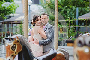 Happy newlyweds huging near the carousel