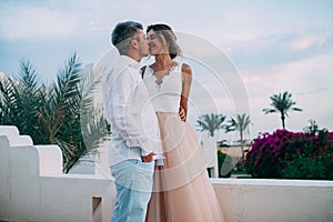 Happy newlyweds kiss on terrace of white villa during the honeymoon