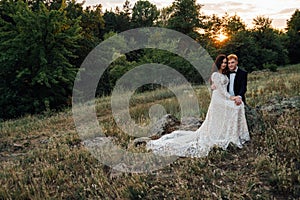Happy newlyweds are sitting on a rock in the nature