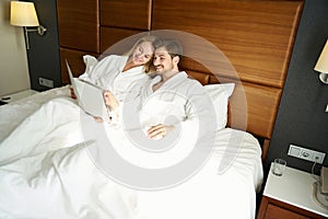 Happy newlyweds study the menu in bed