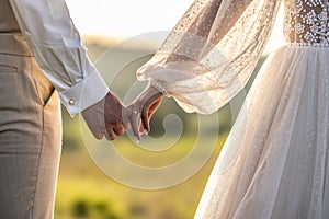 Happy newlyweds walk hand in hand towards their new happy life at sunset