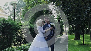 Happy newlyweds walk in the park holding hand, hug kiss.